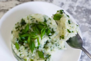 Vejetaryen, vejetaryen, lezzetli yemekler. Beyaz tabakta ıspanaklı ve soğanlı pilav. Gıda tüketimi süreci. Sağlıklı beslenme kavramı.