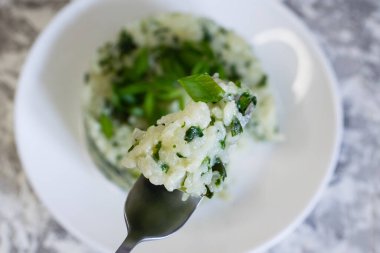 Vejetaryen, vejetaryen, lezzetli yemekler. Beyaz tabakta ıspanaklı ve soğanlı pilav. Gıda tüketimi süreci. Sağlıklı beslenme kavramı.