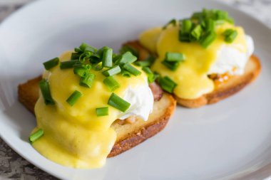 Lezzetli İngiliz kahvaltısı. Soslu yumurta ve domuz pastırması gri bir tabakta kızarmış beyaz ekmek, arka planda yakın plan..