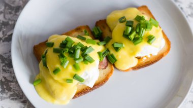 Lezzetli İngiliz kahvaltısı. Soslu yumurta ve domuz pastırması gri bir tabakta kızarmış beyaz ekmek, arka planda yakın plan..