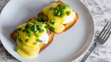 Lezzetli İngiliz kahvaltısı. Soslu yumurta ve domuz pastırması gri bir tabakta kızarmış beyaz ekmek, arka planda yakın plan..