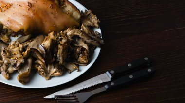 Birayla pişirilmiş domuz şişi ve siyah bir arka planda mantarlar. Tabakta lezzetli bir restoran yemeği.