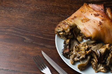 Birayla pişirilmiş domuz budu ve siyah arka planda mantarlar, kopyalama alanı. Tabakta lezzetli bir restoran yemeği.