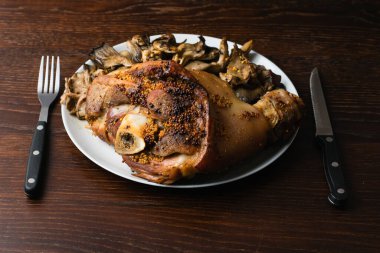 Birayla pişirilmiş domuz şişi ve siyah bir arka planda mantarlar. Tabakta lezzetli bir restoran yemeği.