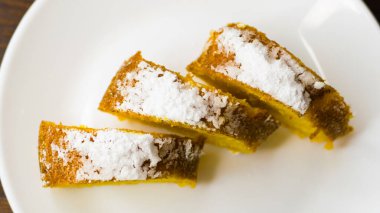 Lezzetli balkabaklı kek. Koyu ahşap bir masada beyaz bir tabakta parçalara ayrılmış..