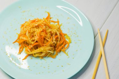 Lezzetli Kore mutfağı. Havuçlu salata ve turkuaz bir tabakta Kore usulü daikon.