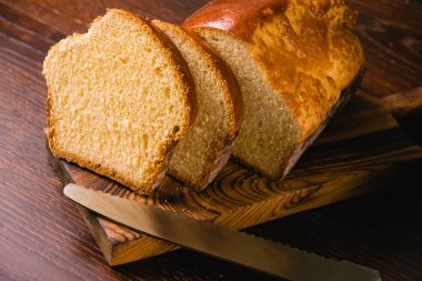 Lezzetli ve tatlı tereyağlı ekmek. Koyu ahşap kesme tahtasıyla dilimlenmiş. Lezzetli ev yapımı yemekler.