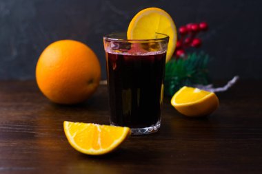 Portakallı, tarçınlı ve ballı lezzetli şarap koyu bir arka planda bir bardakta. Sıcak bir kış akşamı, Noel ve Yeni Yıl kutlaması kavramı.