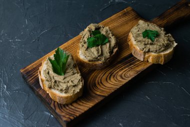 Sağlıklı yemek, lezzetli ve iştah açıcı sandviçler, sığır ciğeri, maydanoz ve koyu ahşap mutfak tahtasının üzerinde çıtır çıtır ekmek.