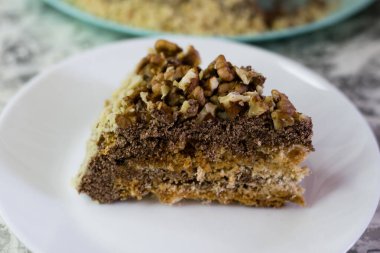 Hafif arka planda kremalı, fıstıklı ve cevizli nefis ev yapımı kek. Beyaz bir tabakta iştah açıcı bir pasta. Doğal ev yapımı pişirme kavramı.