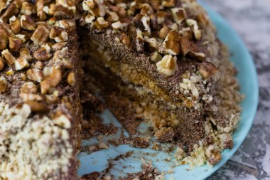 Hafif arka planda kremalı, fıstıklı ve cevizli nefis ev yapımı kek. Mavi bir tabakta dilimlenmiş kek. Doğal ev yapımı pişirme kavramı.