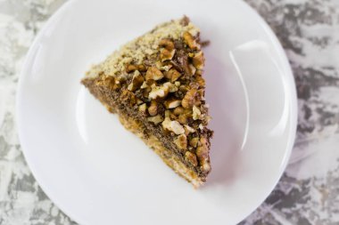 Hafif arka planda kremalı, fıstıklı ve cevizli nefis ev yapımı kek. Beyaz bir tabakta iştah açıcı bir pasta. Doğal ev yapımı pişirme kavramı.