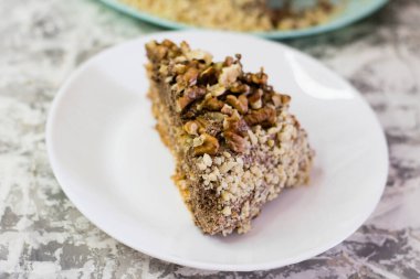 Hafif arka planda kremalı, fıstıklı ve cevizli nefis ev yapımı kek. Beyaz bir tabakta iştah açıcı bir pasta. Doğal ev yapımı pişirme kavramı.