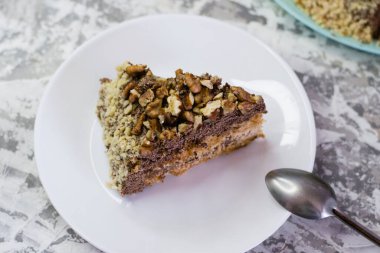 Hafif arka planda kremalı, fıstıklı ve cevizli nefis ev yapımı kek. Beyaz bir tabakta iştah açıcı bir pasta. Doğal ev yapımı pişirme kavramı.