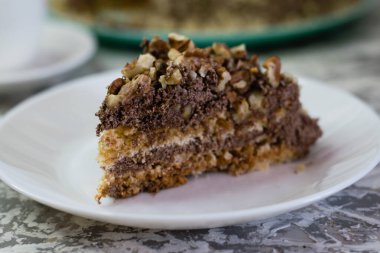 Hafif arka planda kremalı, fıstıklı ve cevizli nefis ev yapımı kek. Beyaz bir tabakta iştah açıcı bir pasta. Doğal ev yapımı pişirme kavramı.