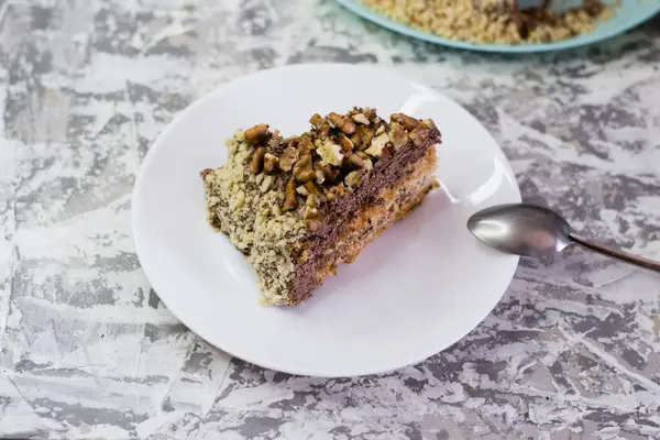 Hafif arka planda kremalı, fıstıklı ve cevizli nefis ev yapımı kek. Beyaz bir tabakta iştah açıcı bir pasta. Doğal ev yapımı pişirme kavramı.