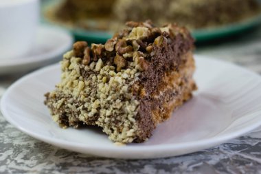 Hafif arka planda kremalı, fıstıklı ve cevizli nefis ev yapımı kek. Beyaz bir tabakta iştah açıcı bir pasta. Doğal ev yapımı pişirme kavramı.