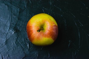 Koyu beton zemin üzerinde parlak sarı elma ve metin için boşluk. Sağlıklı yeme kavramı.