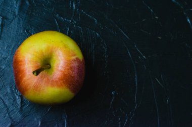 Koyu beton zemin üzerinde parlak sarı elma ve metin için boşluk. Sağlıklı yeme kavramı.