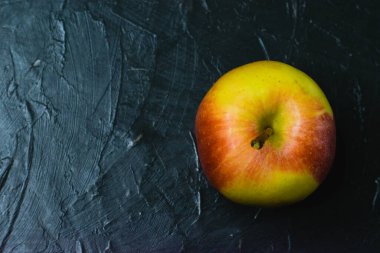 Koyu beton zemin üzerinde parlak sarı elma ve metin için boşluk. Sağlıklı yeme kavramı.