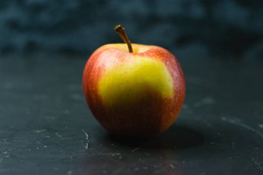 Koyu beton zemin üzerinde parlak sarı elma ve metin için boşluk. Sağlıklı yeme kavramı.