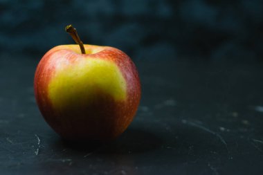 Koyu beton zemin üzerinde parlak sarı elma ve metin için boşluk. Sağlıklı yeme kavramı.