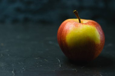 Koyu beton zemin üzerinde parlak sarı elma ve metin için boşluk. Sağlıklı yeme kavramı.