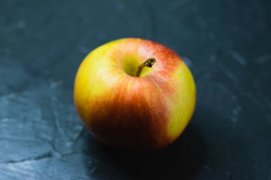 Koyu beton zemin üzerinde parlak sarı elma ve metin için boşluk. Sağlıklı yeme kavramı.