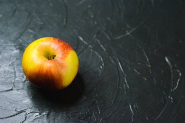 Koyu beton zemin üzerinde parlak sarı elma ve metin için boşluk. Sağlıklı yeme kavramı.