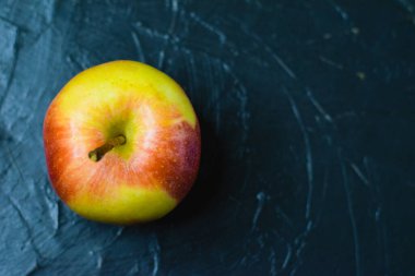 Koyu beton zemin üzerinde parlak sarı elma ve metin için boşluk. Sağlıklı yeme kavramı.