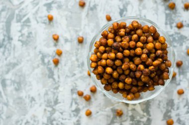 Masanın üzerinde şeffaf bir kâse içinde nefis pişmiş nohutlar, arka planda düz yazı için yer var. Sağlıklı yeme kavramı