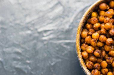 Lezzetli aperatif, esmer bir çanakta baharatlı nohut ile pişirilmiş koyu bir arka planda, yazı için yeri olan. Sağlıklı yeme kavramı