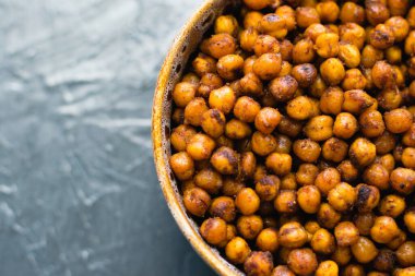 Lezzetli aperatif, esmer bir çanakta baharatlı nohut ile pişirilmiş koyu bir arka planda, yazı için yeri olan. Sağlıklı yeme kavramı