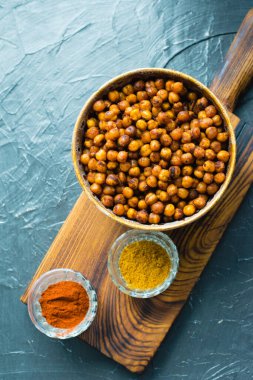 Lezzetli aperatifler, köri baharatları ve kahverengi bir kasede füme paprika nohutları ile pişirilmiş mis mis kokulu kokulu yemekler ve yazı için yeri olan koyu bir arka planda baharatlar. Sağlıklı yeme kavramı