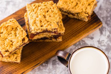 Elma reçelli nefis ev yapımı turta. İştah açıcı rendelenmiş turta dilimleri, ahşap bir tahtada reçel ve bir bardak süt.
