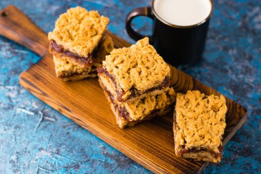 Elma reçelli nefis ev yapımı turta. İştah açıcı rendelenmiş turta dilimleri, tahta tahtada reçel ve masada bir fincan süt.