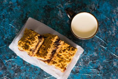 Elma reçelli nefis ev yapımı turta. Tahtaya reçel konmuş rendelenmiş turtanın iştah açıcı dilimleri ve masada bir fincan süt.