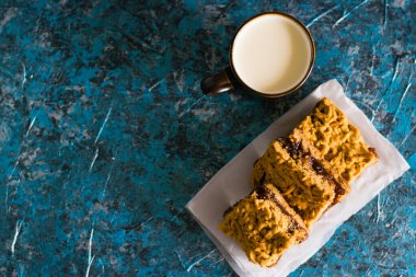 Elma reçelli nefis ev yapımı turta. Tahtaya reçel konmuş rendelenmiş turtanın iştah açıcı dilimleri ve masada bir fincan süt.