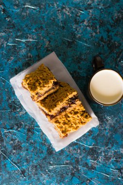 Elma reçelli nefis ev yapımı turta. Tahtaya reçel konmuş rendelenmiş turtanın iştah açıcı dilimleri ve masada bir fincan süt.