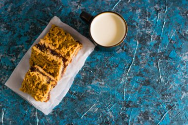 Elma reçelli nefis ev yapımı turta. Tahtaya reçel konmuş rendelenmiş turtanın iştah açıcı dilimleri ve masada bir fincan süt.