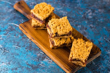 Elma reçelli nefis ev yapımı turta. Ahşap bir tahtanın üzerinde reçelli rendelenmiş turta parçaları, yakın plan elma ve tarçın aroması..