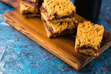 Elma reçelli nefis ev yapımı turta. Ahşap bir tahtanın üzerinde reçelli rendelenmiş turta parçaları, yakın plan elma ve tarçın aroması..