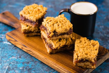 Elma reçelli nefis ev yapımı turta. İştah açıcı rendelenmiş turta dilimleri, tahta tahtada reçel ve masada bir fincan süt.
