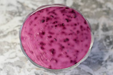 Açık arkaplanda şeffaf bir kasede pembe tatlı. Frenk üzümlü yaz tatlısı.