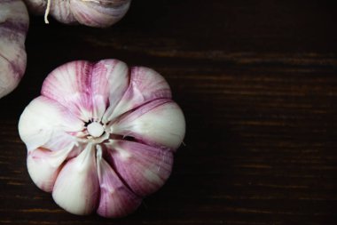 Kabuğu soyulmamış sarımsak karanfilleri yakın planda, tahtadan bir masada..