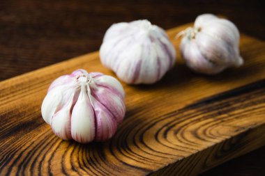 Kabuğu soyulmamış sarımsak karanfilleri yakın planda, tahtadan bir masada..