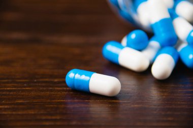 Karanlık bir arka plan makrosu üzerinde bir sürü hap. Ahşap arka planda beyaz ve mavi vitamin hapları. Kendi kendine tedavi konsepti