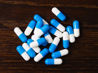 Karanlık bir arka plan makrosu üzerinde bir sürü hap. Ahşap arka planda beyaz ve mavi vitamin hapları. Kendi kendine tedavi konsepti