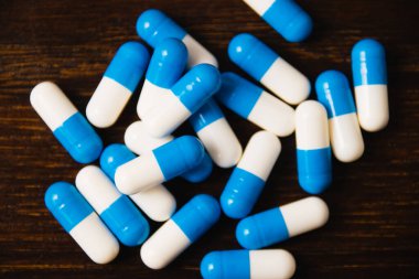 Karanlık bir arka plan makrosu üzerinde bir sürü hap. Ahşap arka planda beyaz ve mavi vitamin hapları. Kendi kendine tedavi konsepti