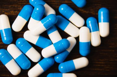 Karanlık bir arka plan makrosu üzerinde bir sürü hap. Ahşap arka planda beyaz ve mavi vitamin hapları. Kendi kendine tedavi konsepti